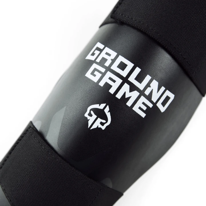 Zbliżenie na logo Ground Game na czarnym ochraniaczu golenia Cyborg