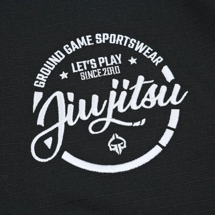 Detale nadruku okrągłego logo Ground Game Jiu-Jitsu na czarnych spodenkach