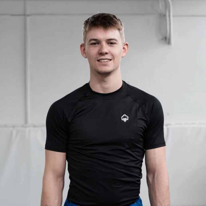 Mężczyzna w czarnym rashguardzie Ground Game Essential Platinum na macie do sportów walki