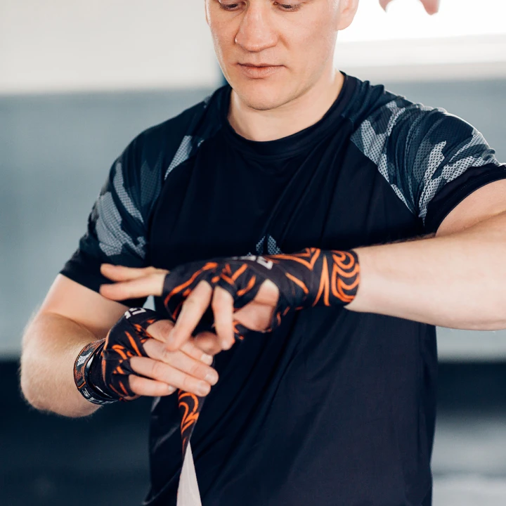 Zawodnik wiążący bandaże owijki bokserskie 4 m Ground Game Flames na dłoniach