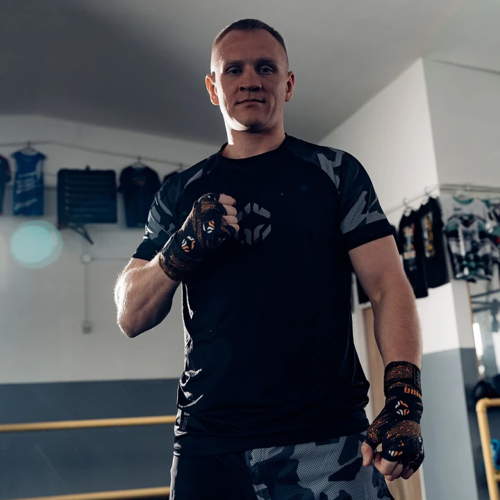 Zawodnik w rękawicach i zawiązanych owijkach bokserskich Ground Game Samurai w sali treningowej