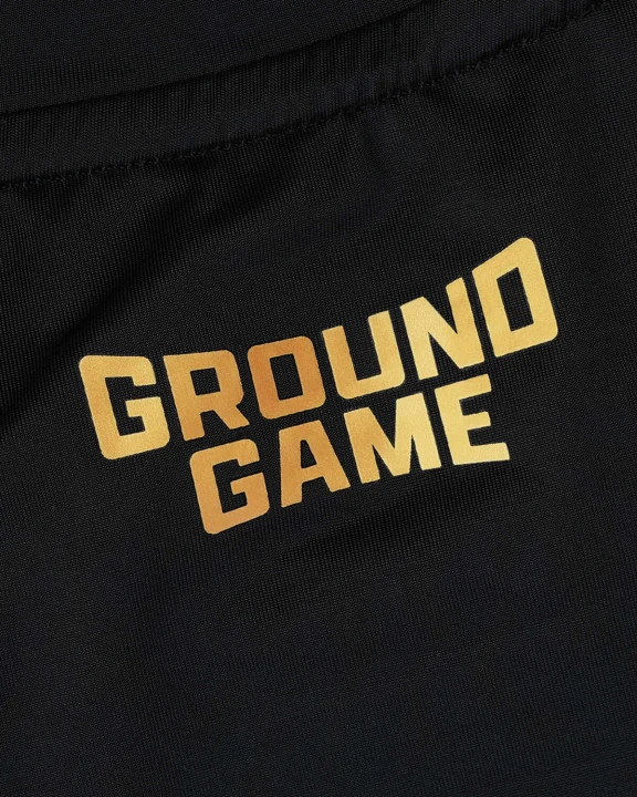 Złote logo i napis Ground Game na piersi rashguarda Essential Gold